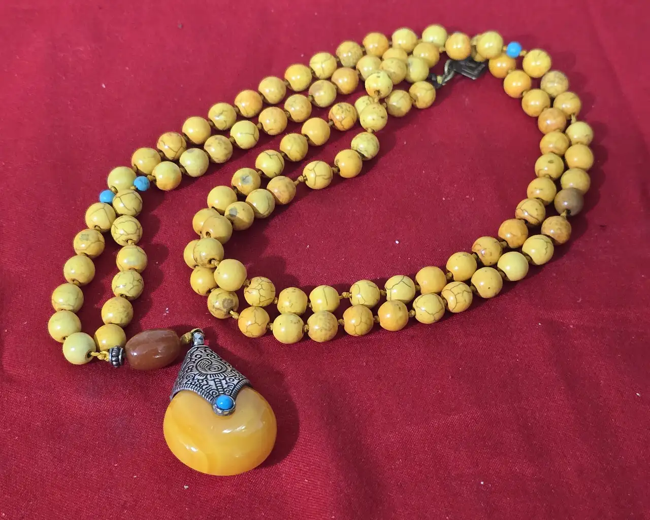 שרשרת חרוזים צהובה הכוללת 108 חרוזים משמשת בבודהיזים ובהינדונזים לספיר אורך המחרוזת 50 ס'מה לתפילה החרוזים אבן עינבר או חרוזי כורכום כולל גם תליון גדול אם אלמנט של כסף טיבטי