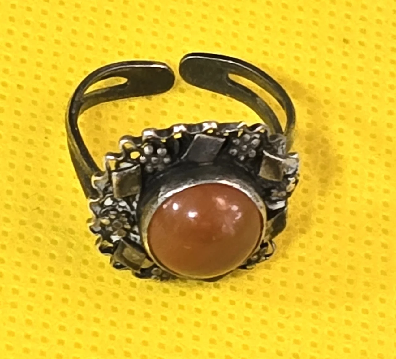 טבעת כסף עדינה ויפה, משובצת אבן אגת ומעוטרת מסביב בדוגמאות פרחים ומעוינים קטנים.  לא נמצאה חתימה.  מידת הטבעת: מתכווננת  משקל: 4.18 גרם.