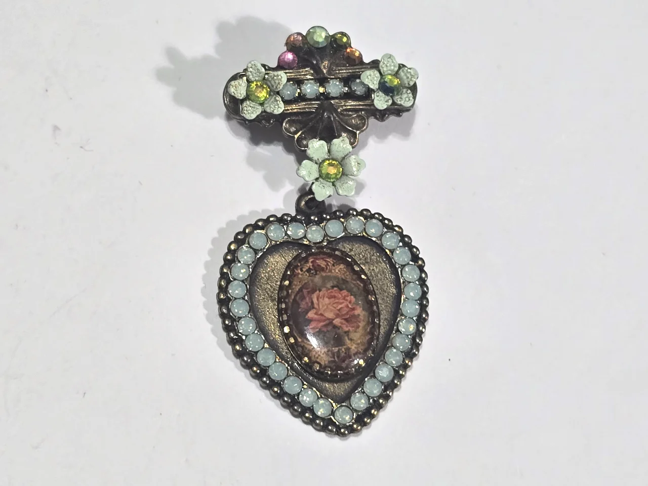 סיכה מבית מיכל נגרין חלק תחתון צורת לב באמצע אמאייל שבתוכו ורד ומסביב אבני סברובסקןי ירוקים חלק עליון פרחים עם אבני סברובסקי נדירה