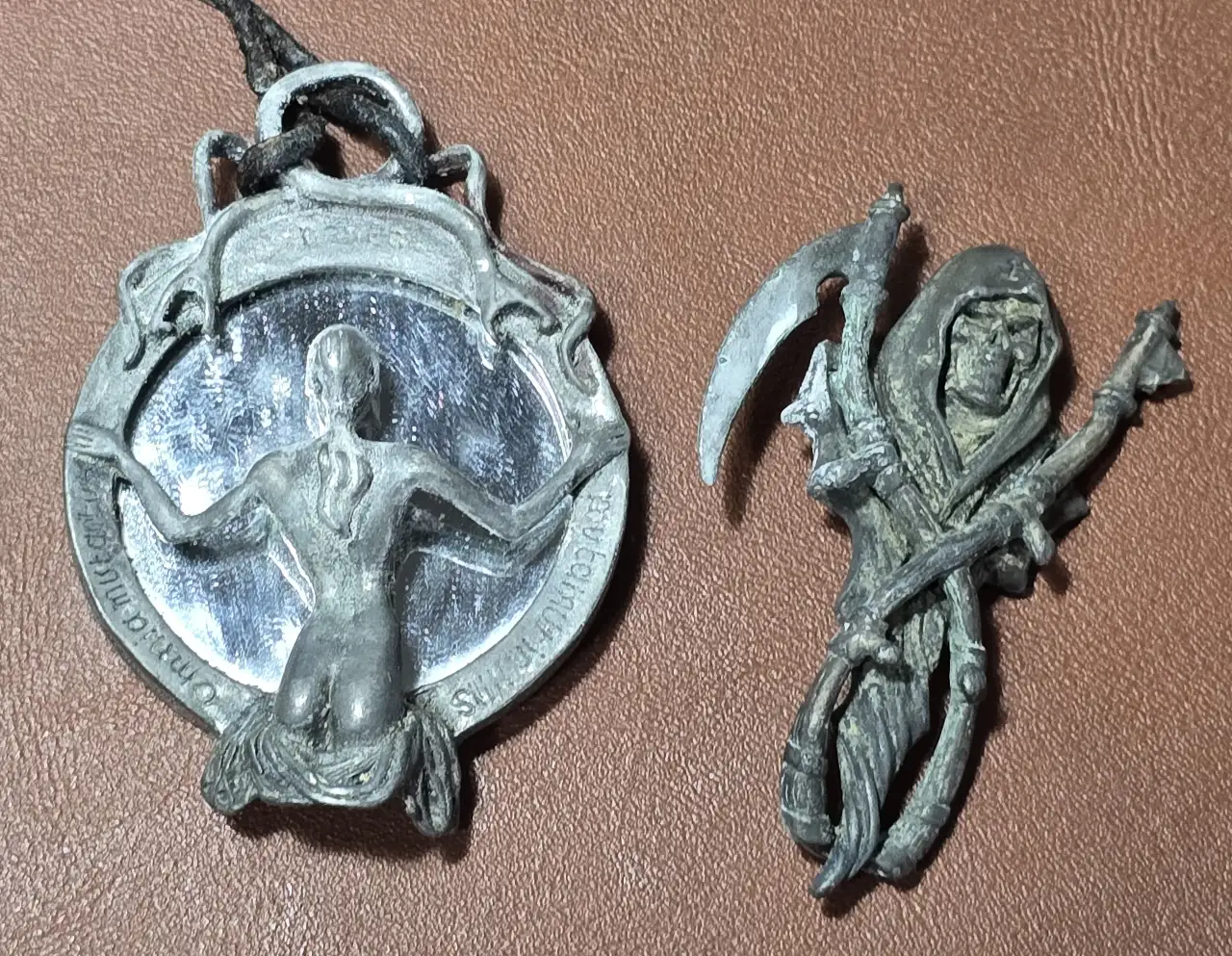 תליון מראה דמות נשית מביטה אל תוך המראה עשוי מפיוטר והדמות השניה מלאך המוות