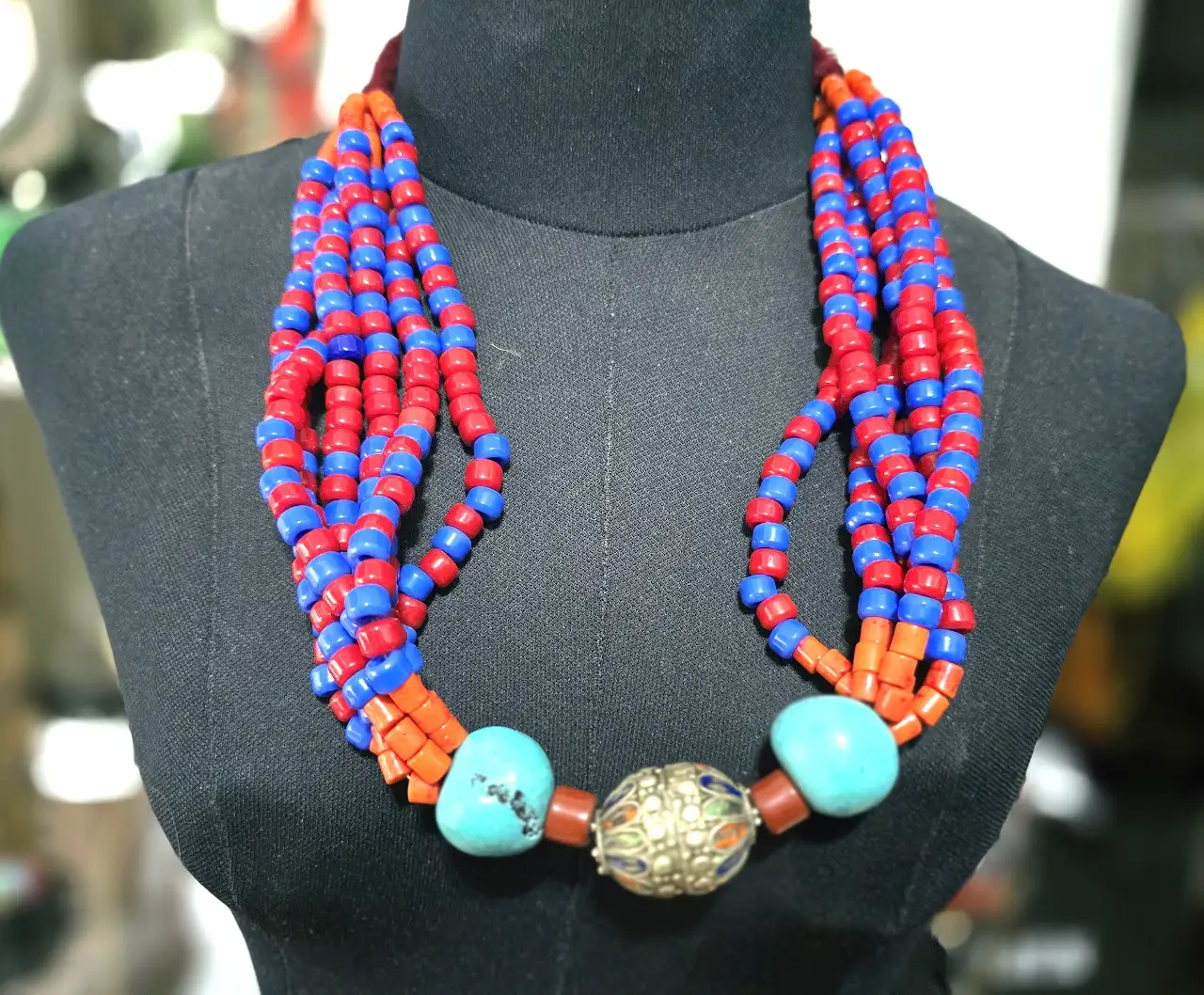 שרשרת תכשיט מרשים בסגנון אתני טיבט נפאל או צפון אפריקה השרשרת מורכבת מריבוי שורות של חרוזים קטנים בצבע אדום וכחול עזים חרוזי טורכיז בחלק התחתון