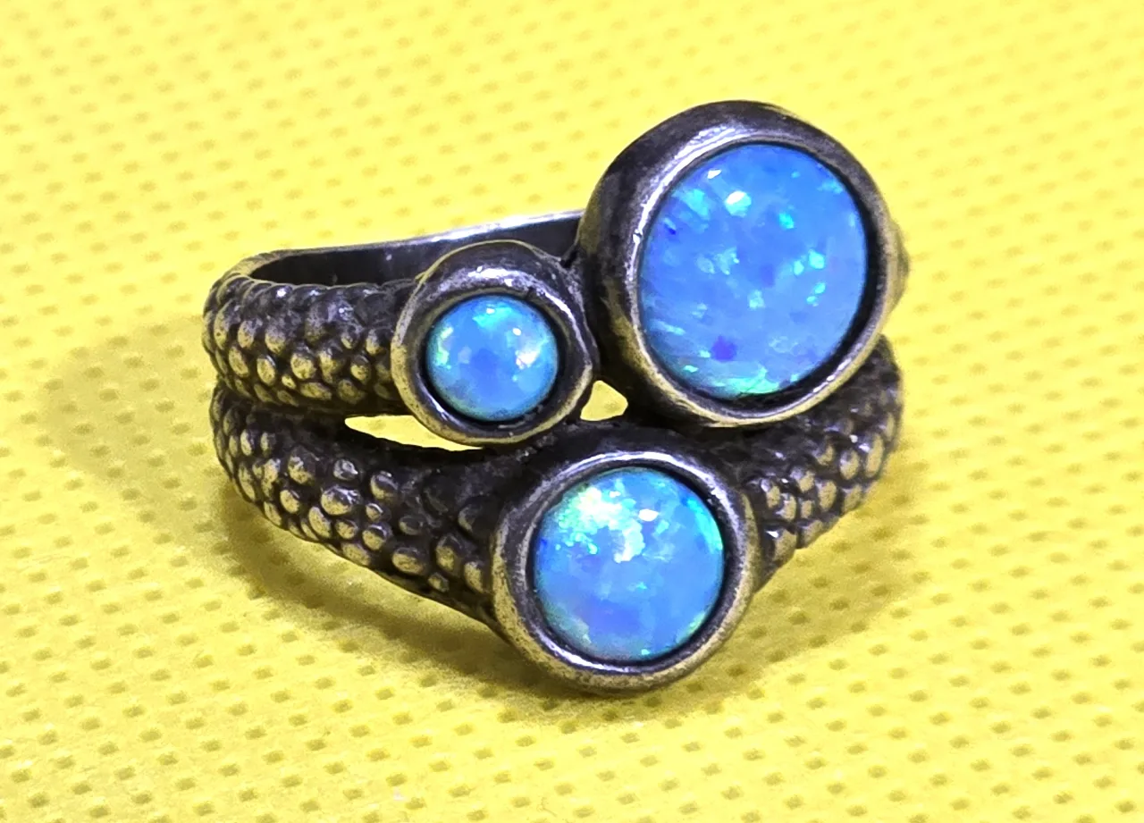 טבעת כסף 925 של חברת שבלול חתומה, משובצת בשלושה אבני אופל בחיתוך קבושון, מעוטרת דמוי עור נחש, מידה 8 חדשה.