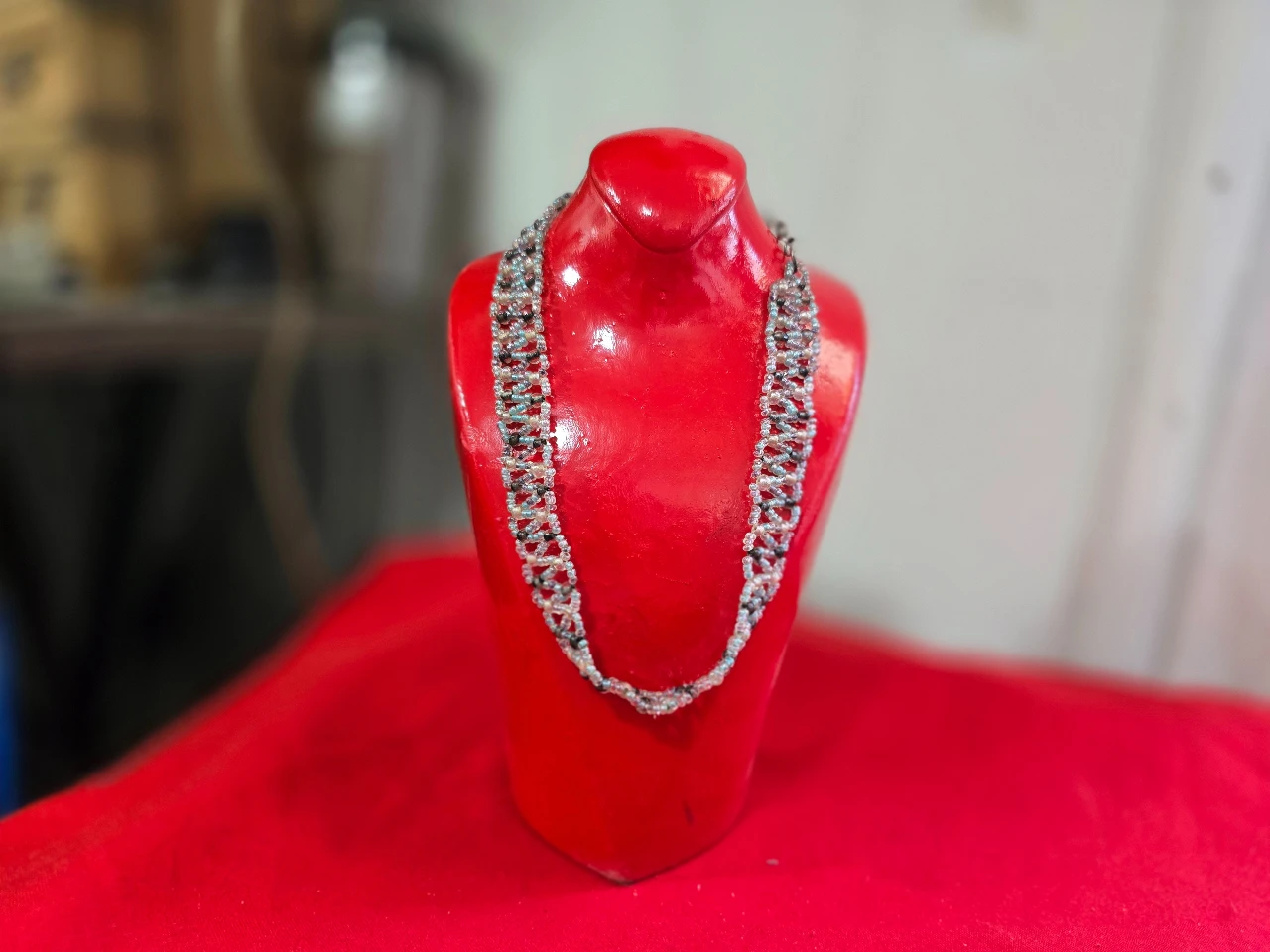 שרשרת בסגנון צ'וקר (Choker) או שרשרת קולר עשויה בעבודת יד חרוזי ונציה קטנים בגוון לבן שחור ואדום התכשיט מאופיין בדוגמת אריגה