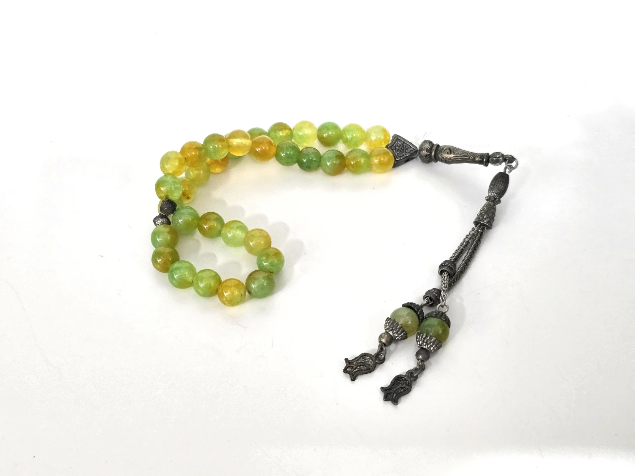 מסבחה תפילה איסלאמית ישנה, מורכבת מ-33 חרוזי זכוכית עגולים בגוונים ירוק-צהוב, משולבת חלקי מתכת בקצה, אורך כולל: 25 ס"מ, קוטר כל חרוז: 6 מ"מ, משקל כולל: 35 גר'.