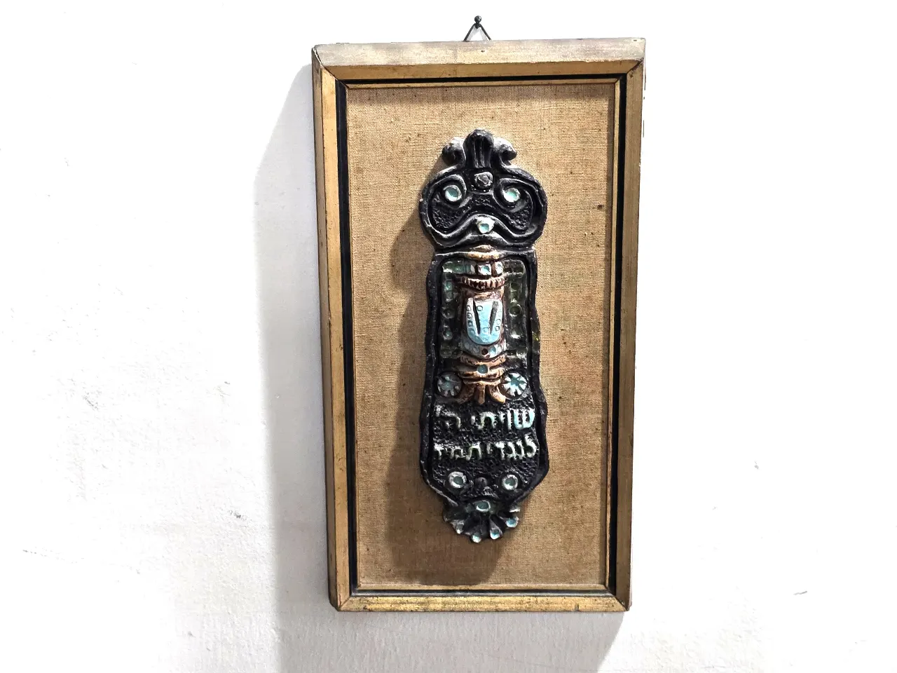 בית מזוזה גדול נתון במסגרת עץ כנראה קרמיקה בשילוב אמייל מידות 32*17