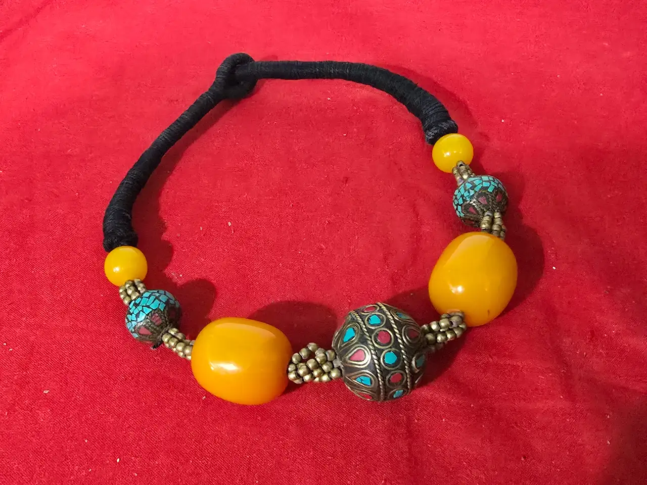 שרשרת בעלת מראה אתני אזור טיבט נפאל או מרכז אסיה החרוזים בגוון צהוב הם חרוזיח ענבר בנוסף אבני טורקיז התכשיט מושחל על שרוך בד שחור