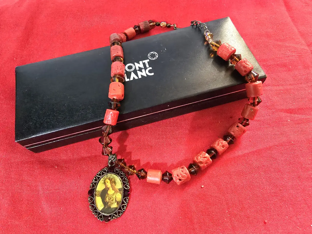 שרשרת בסגנון עתיק עם תליון המציג דמות נסיכה עשויה מחרוזי אלמוג אדומים בצורת גליל וחרוזי גראנט כהים יותר שמפרידים בינהים