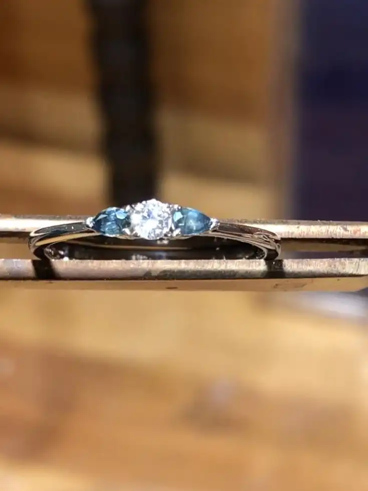 White gold ring with a a diamond and 2 sapphire stones.