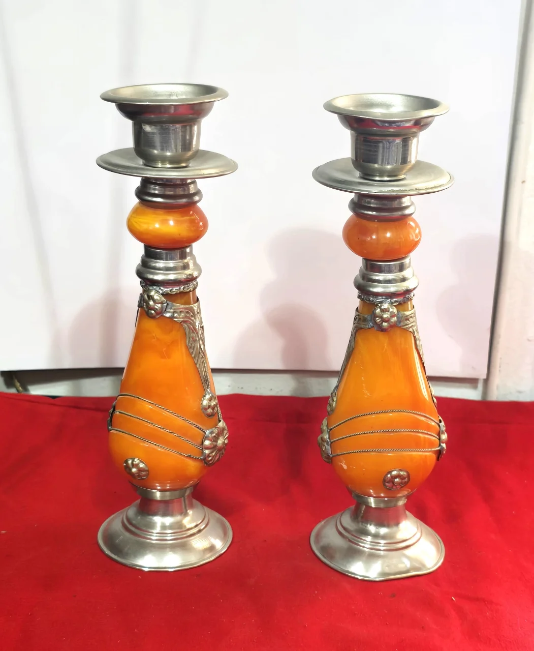 זוג פמוטי שבת מרוקאיםי, עשויים זכוכית בצבע ענבר ופיוטר(ייתכן חומר שרף כלשהו, לא נבדק לעומק), עבודת יד.   מעוטר בקישוטי מתכת וחוטי מתכת דקים כרוכים סביב הפמוטים.