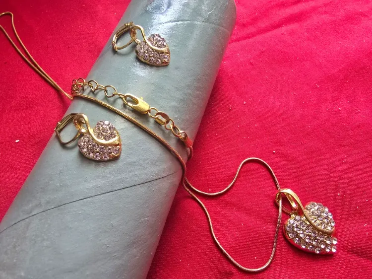 סט מרהיב ובעל נוכחות שרשרת ועגילים בציפוי זהב 18 K שרשרת באורך 60 ס'מ מצב פתוח תליון מרכזי גדול בעיצוב לב משובץ באבני זרקוניה בליטוש יהלום 