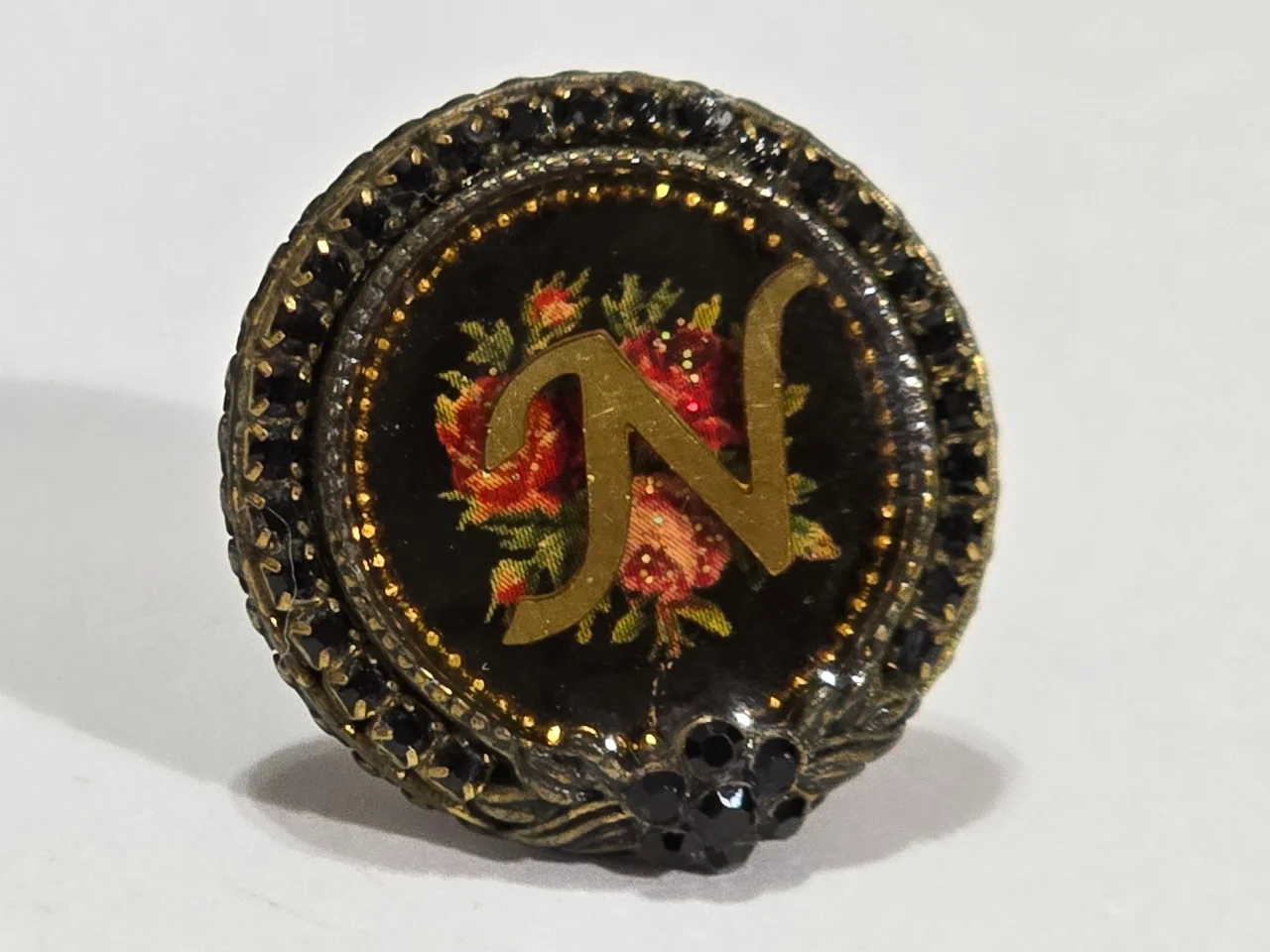 טבעת מבית מיכל נגרין חתומה הטבעת מתכווננת משובצת זרקטנים של סברובסקי מעוטרת בפרח ואמיאל עם ורדים והאות N