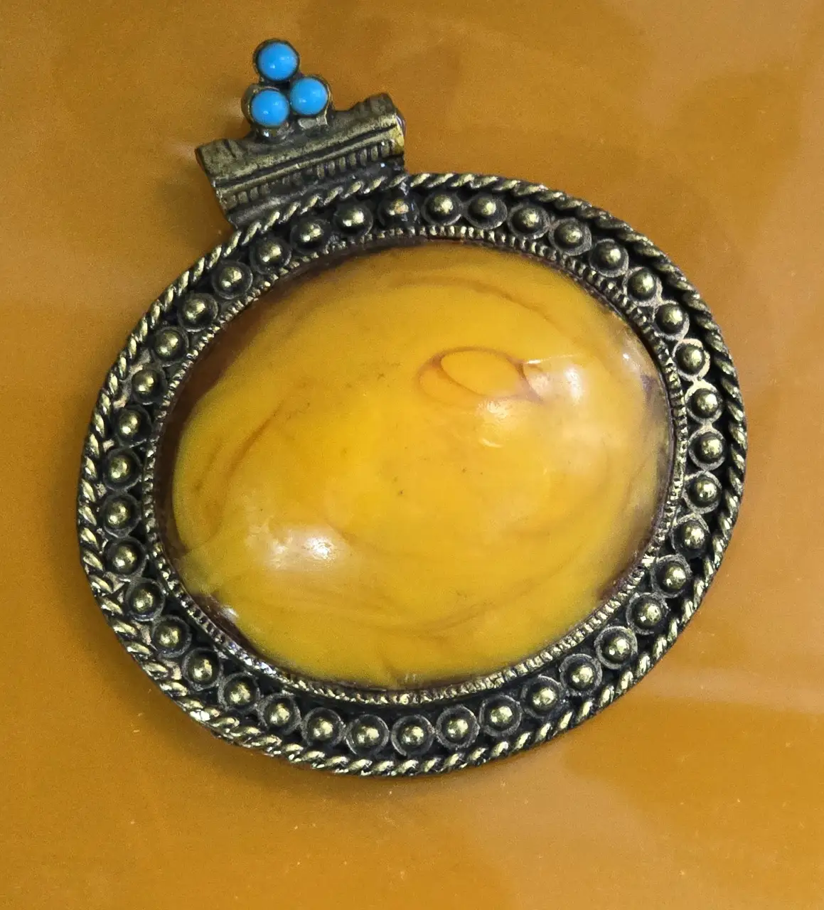 תליון גדול דמוי ענבר אובלי ו 3 אבני טורקיז משובצים על בסיס מתכת . 8.5×7.5×2.5 ס"מ