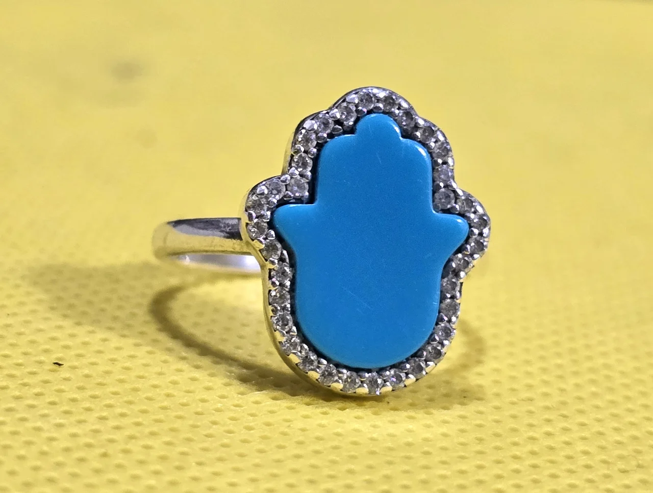 טבעת חמסה כסף 925 חתומה, משובצת טורקיז בליטוש חמסה ומסביב אבני זירקון עגולות קטנות.