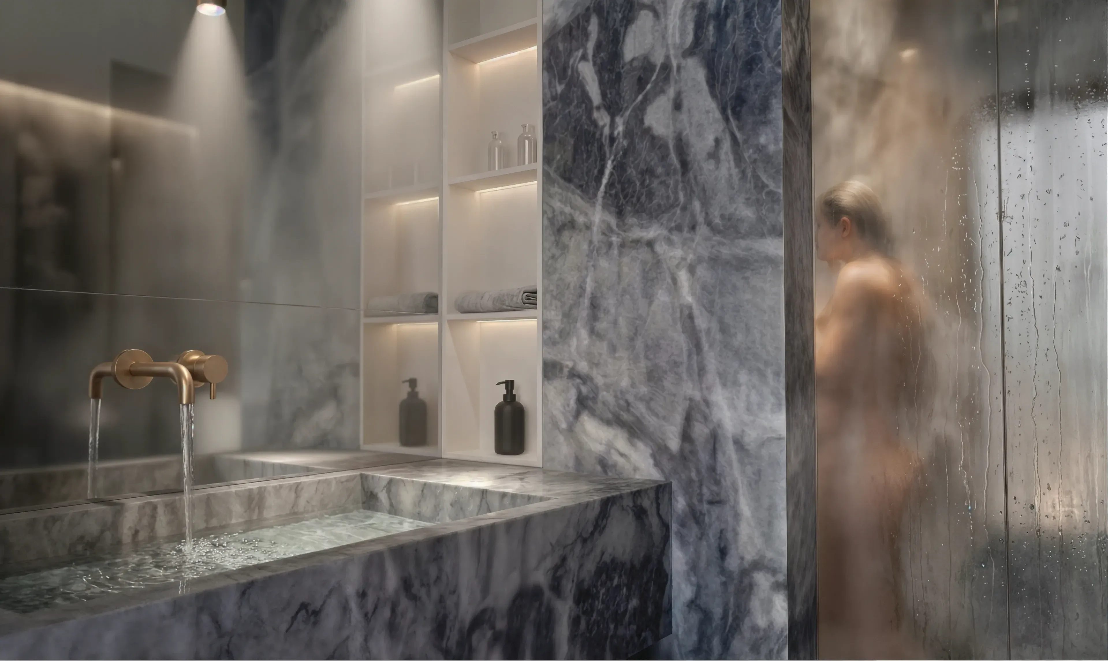 Monolithisches Badezimmer aus blauem Marmor mit Bronze-Armatur und beleuchteten Regalen.