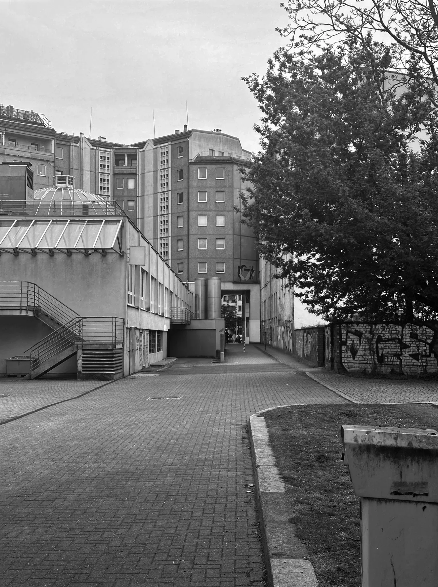 Schwarz-Weiß-Fotografie des unsanierten Ist-Zustandes der Dreispitzpassage mit vollständig versiegelter Asphaltfläche.