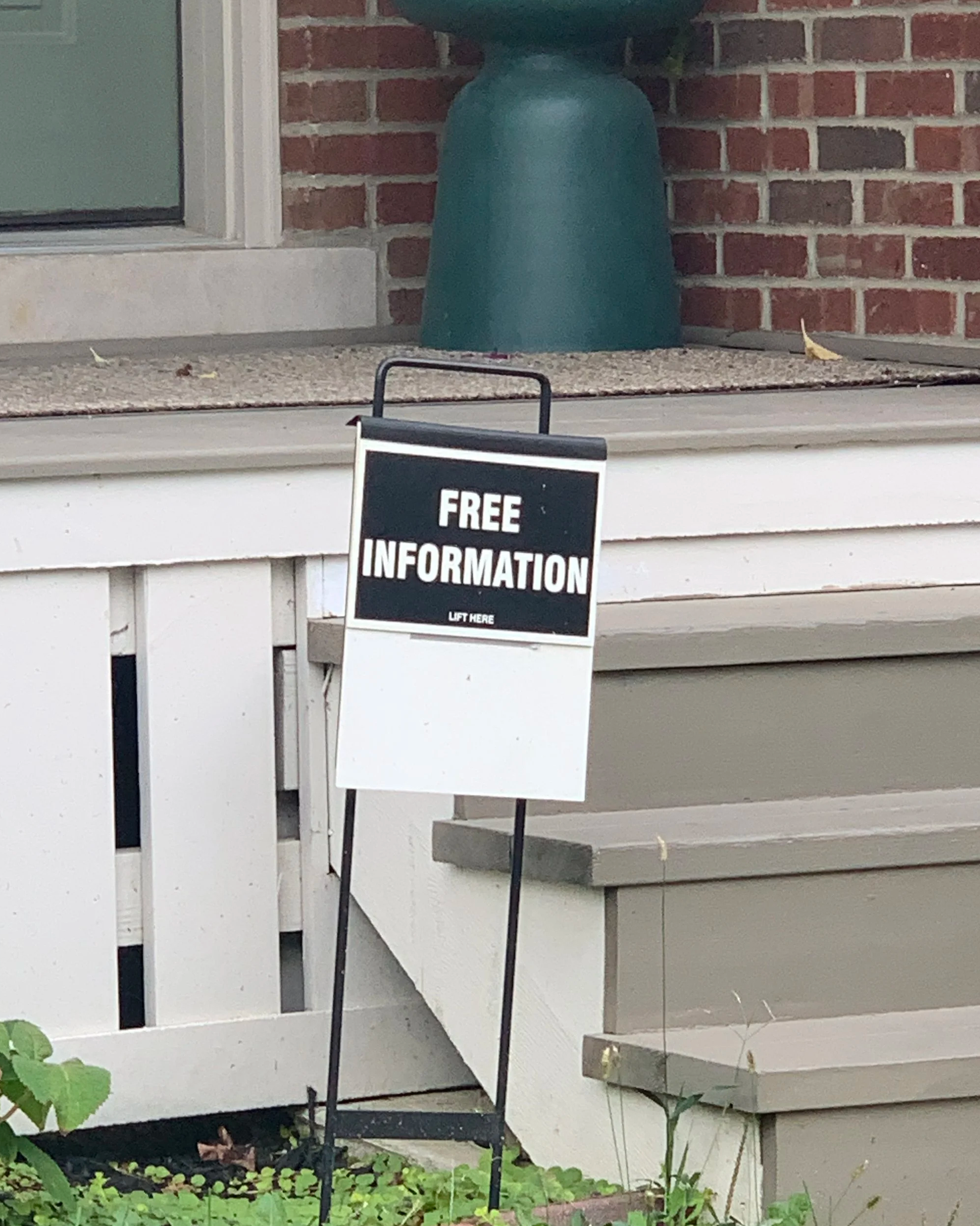 A sign in front of a home that says “Free Information” in white text against a black background