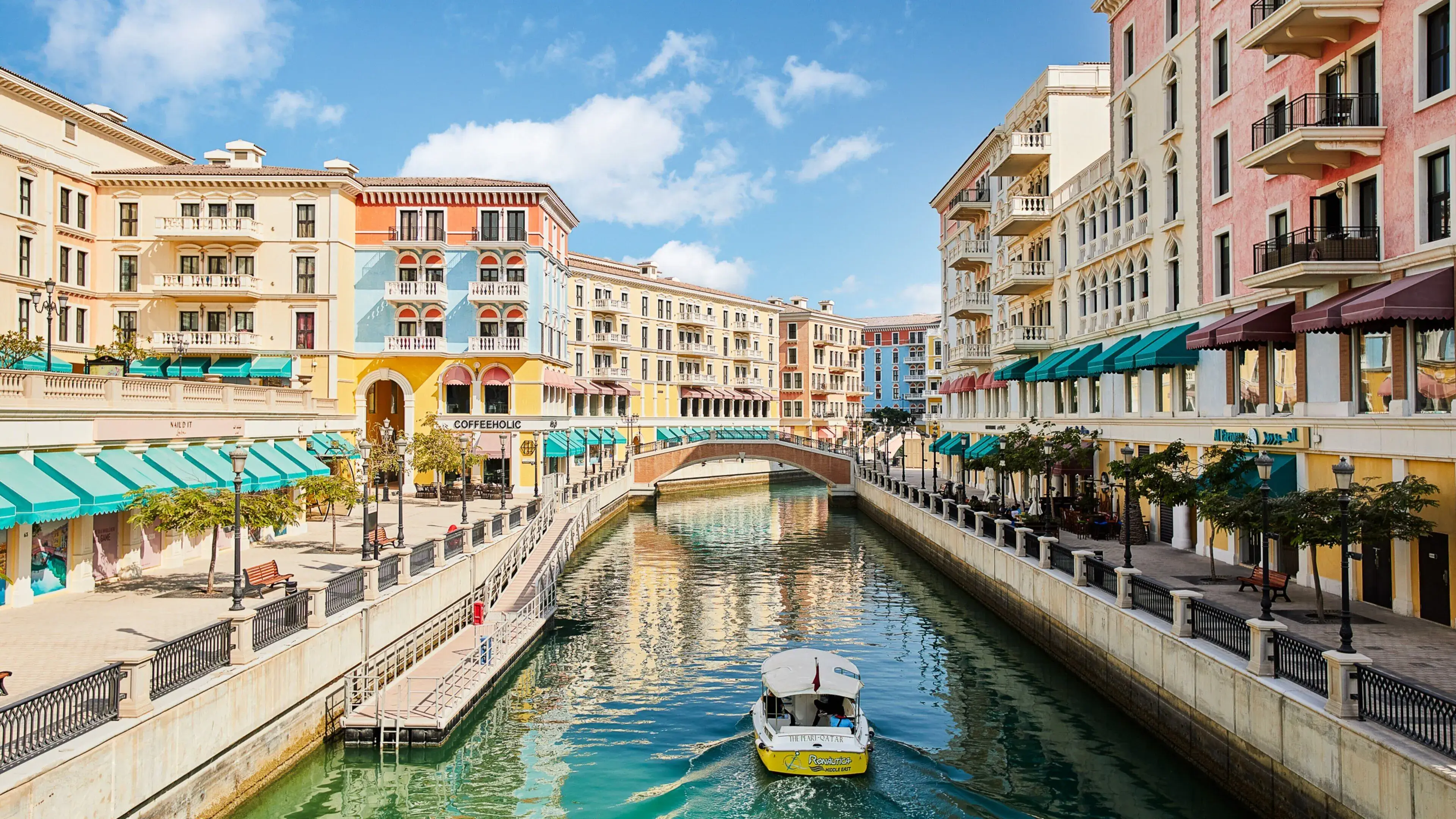 Scenic view of The Pearl-Qatar featuring Venice-style canals, waterfront pathways, and elegant residential buildings along the lakeside.