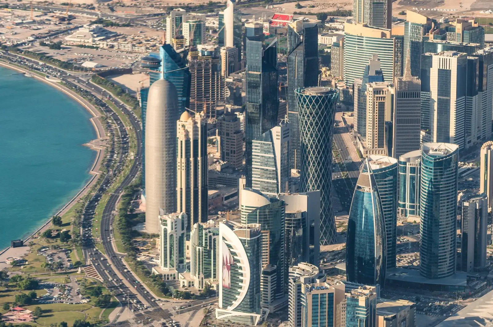 Aerial view of Doha skyline featuring modern skyscrapers, waterfront buildings, and the cityscape along the Arabian Gulf.