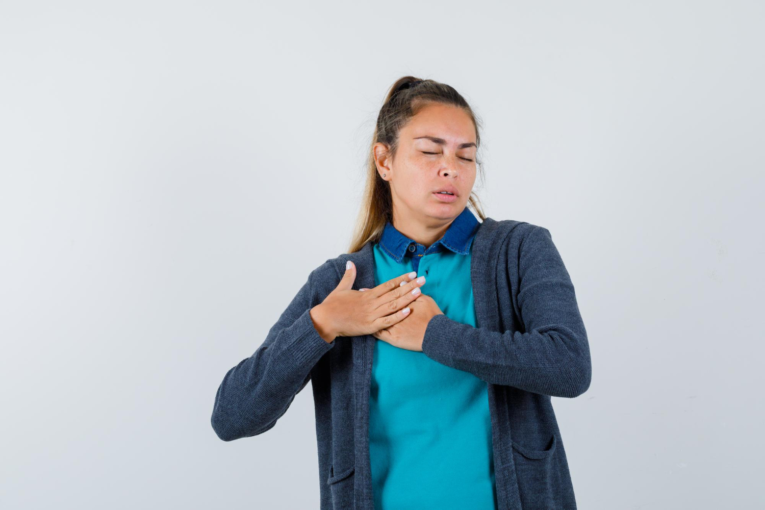 A young adult holding their chest and breathing heavily during a panic attack.