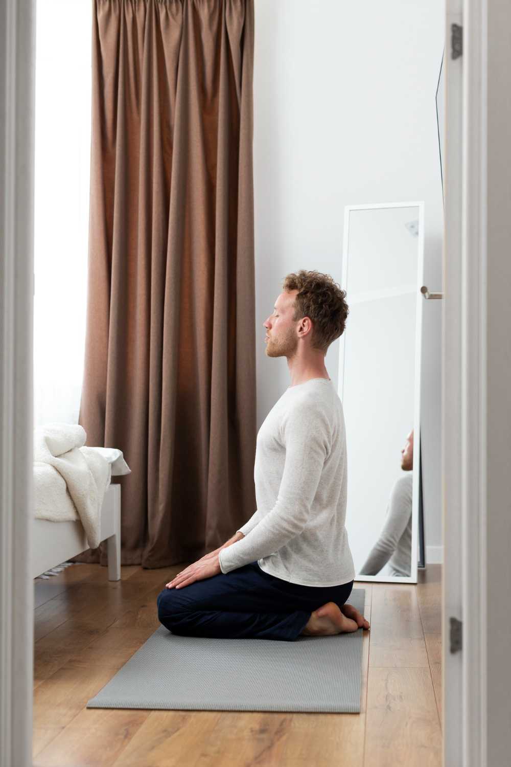 Person meditating at home with eyes closed and calm surroundings.
