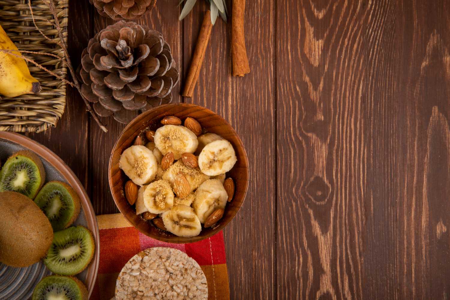 A bowl of bananas, spinach, avocados, and sweet potatoes on a wooden table.