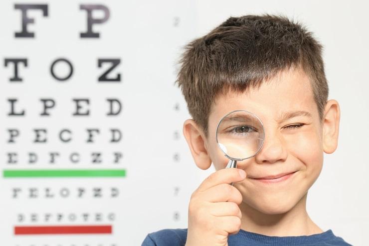 Child holding a magnifying glass to his eye