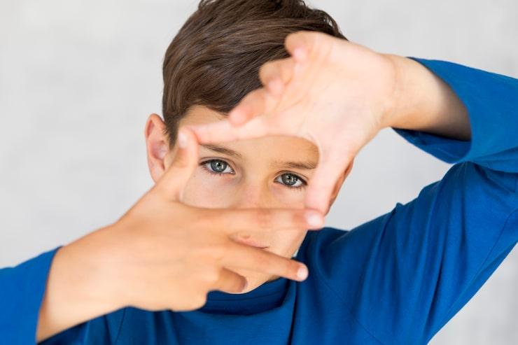 Child forming a frame around his eyes with hands