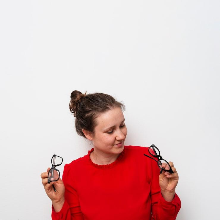 woman holding two pairs of glasses