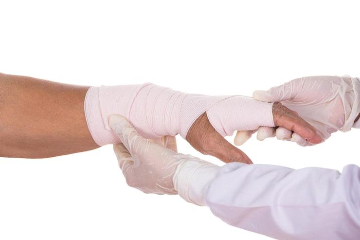 a hand in a bandage being examined by a doctor