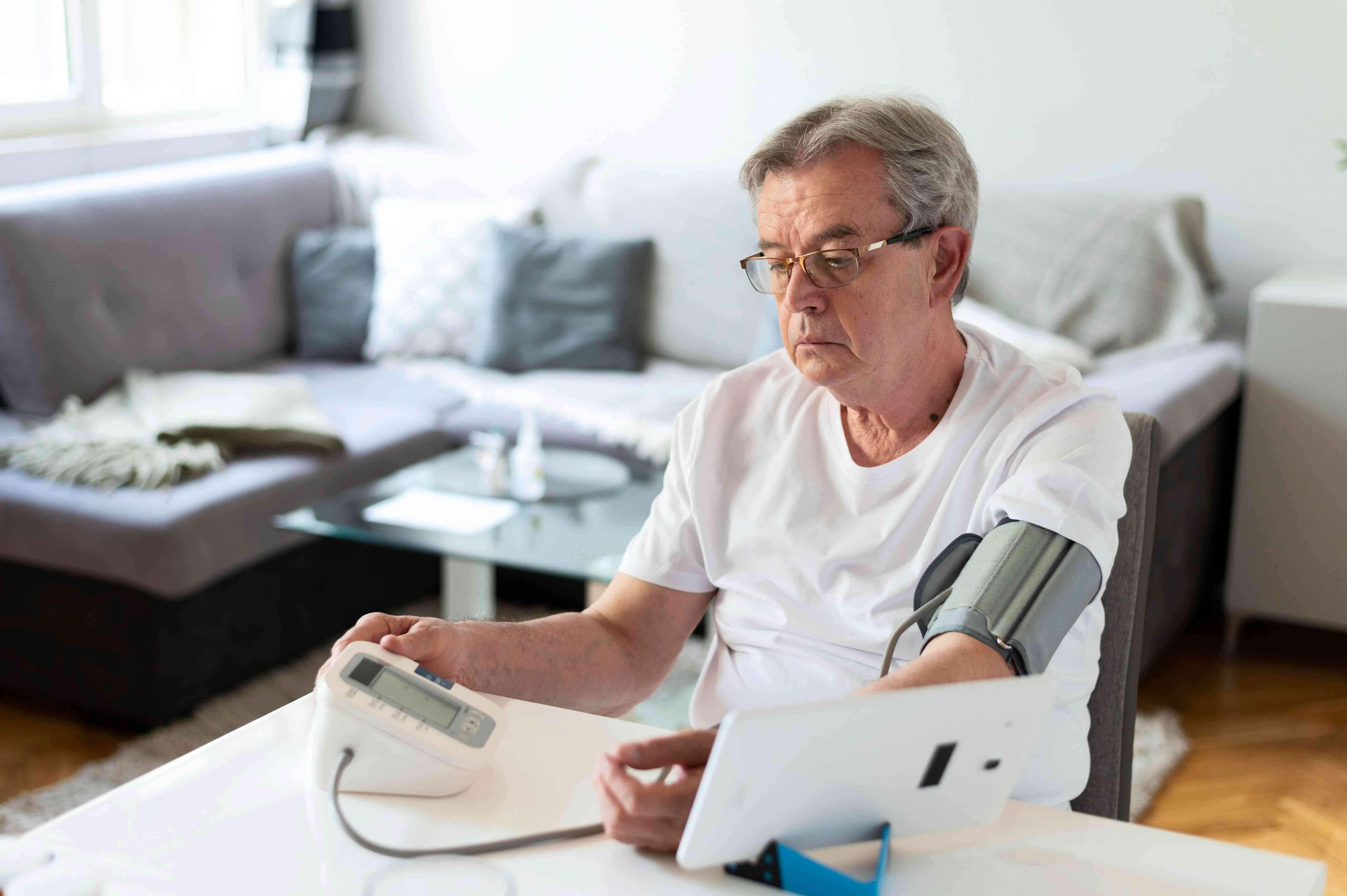 A Senior man checking his blood pressure at home.