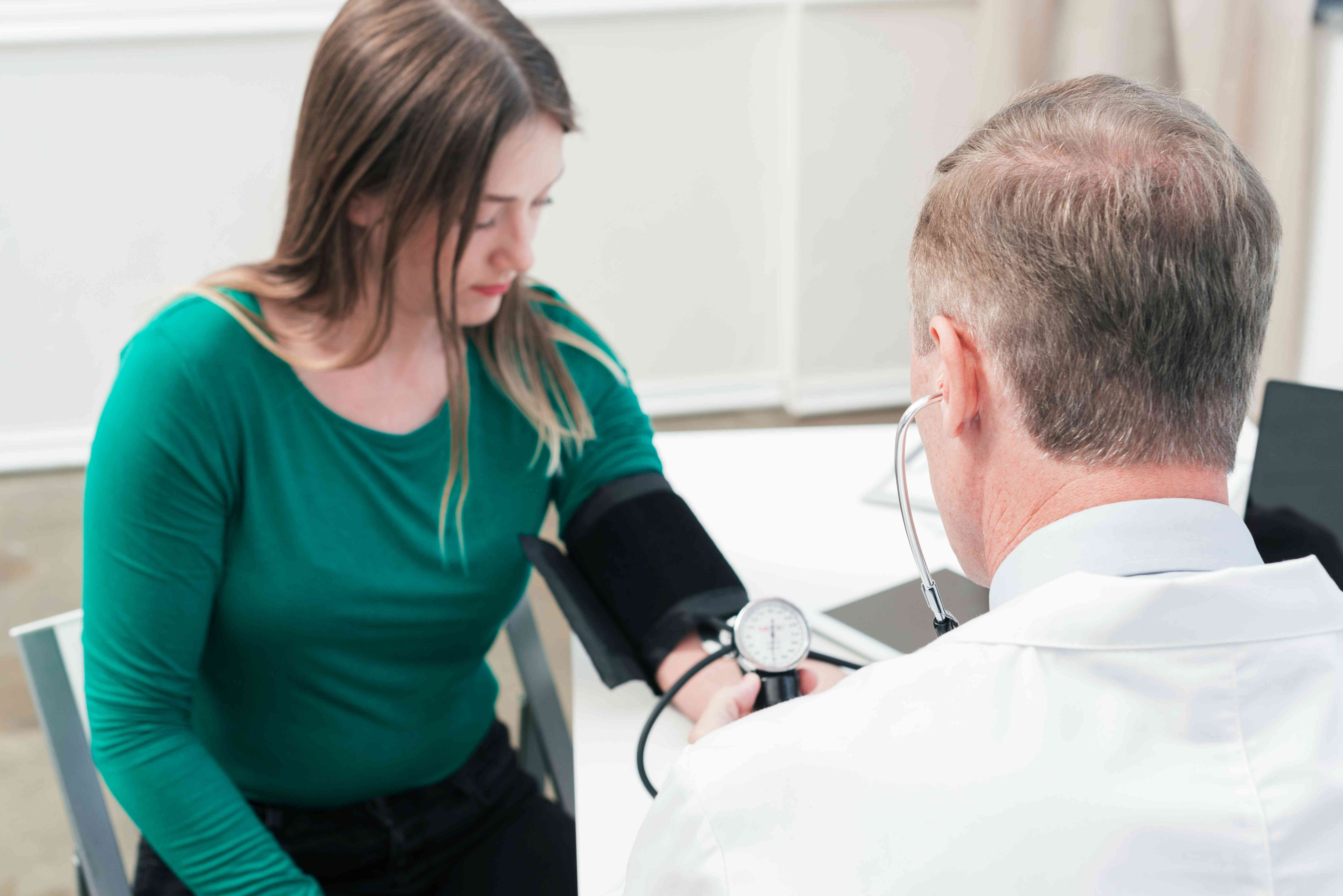 **Doctor measuring a young woman's blood pressure during a medical checkup.
