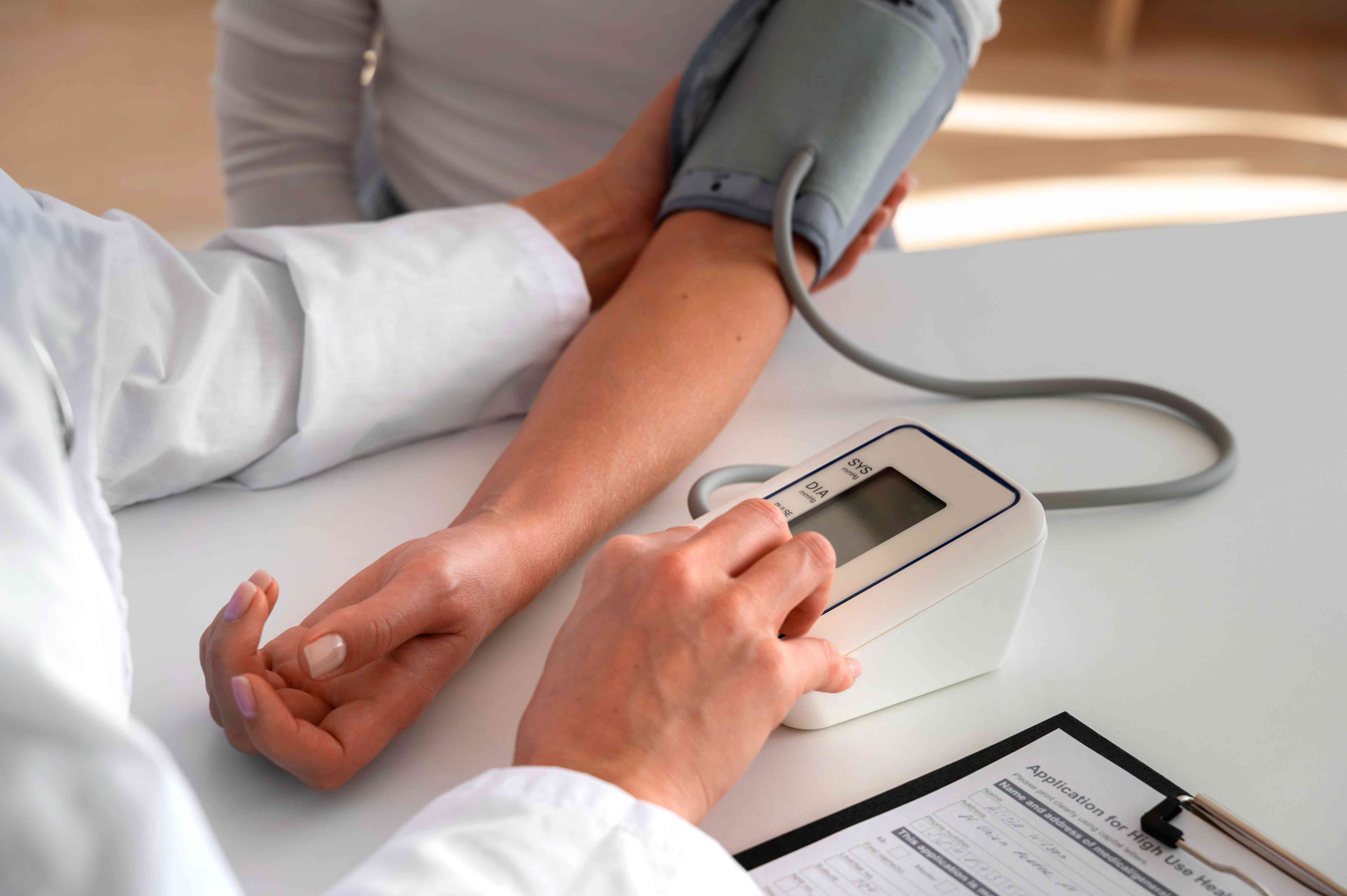 **Close-up of a doctor using a digital blood pressure monitor on a patient’s arm.