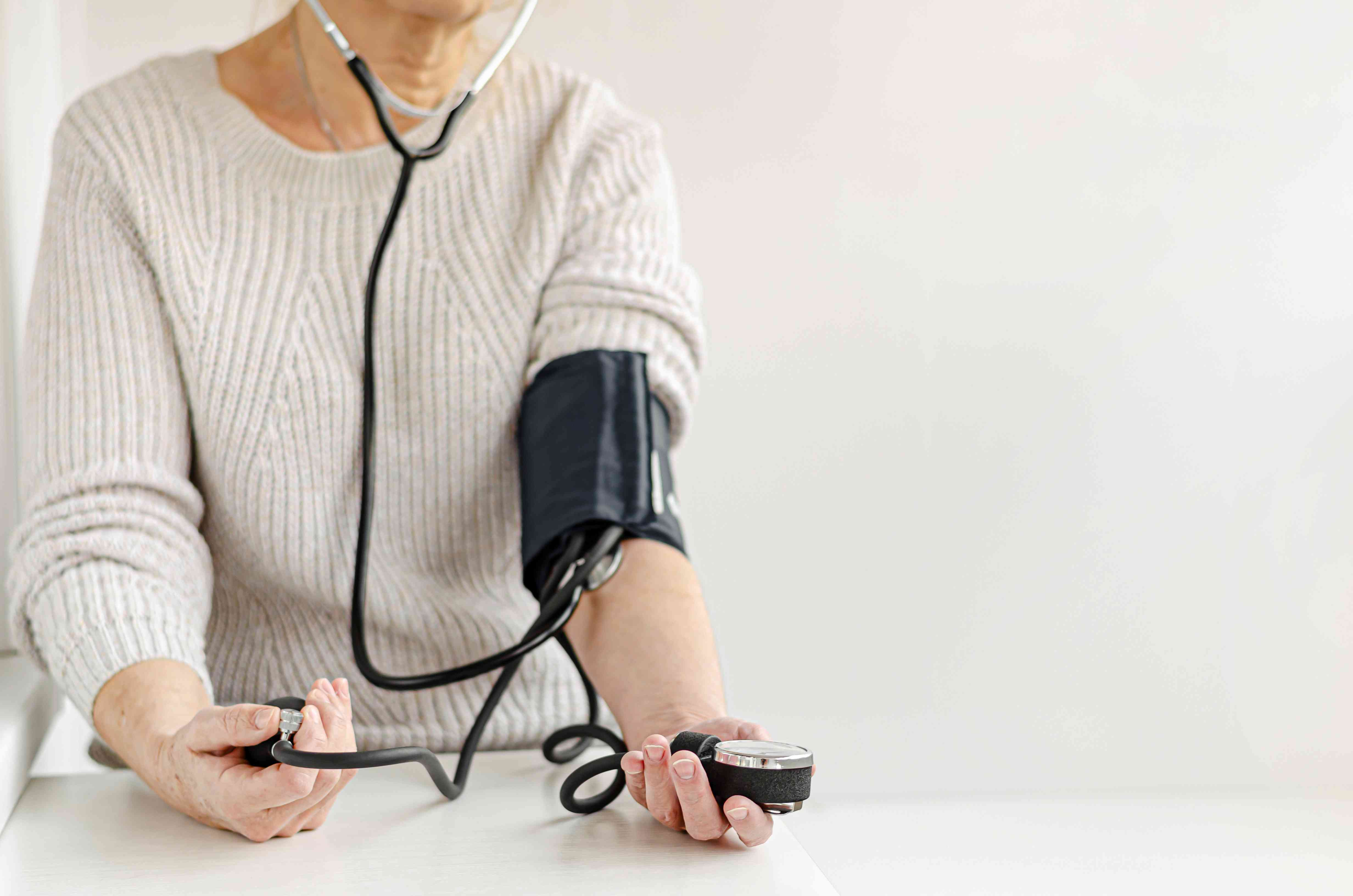 **Older woman self-checking her blood pressure with a manual device.