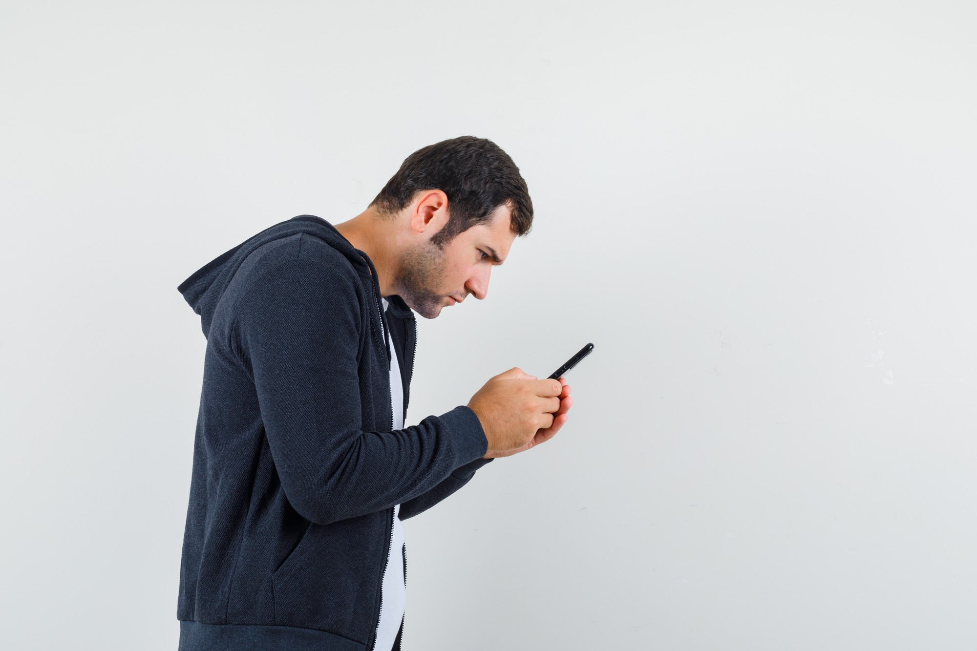 A man bending his head forward while using a smartphone, illustrating neck strain caused by prolonged screen time, also known as tech-neck