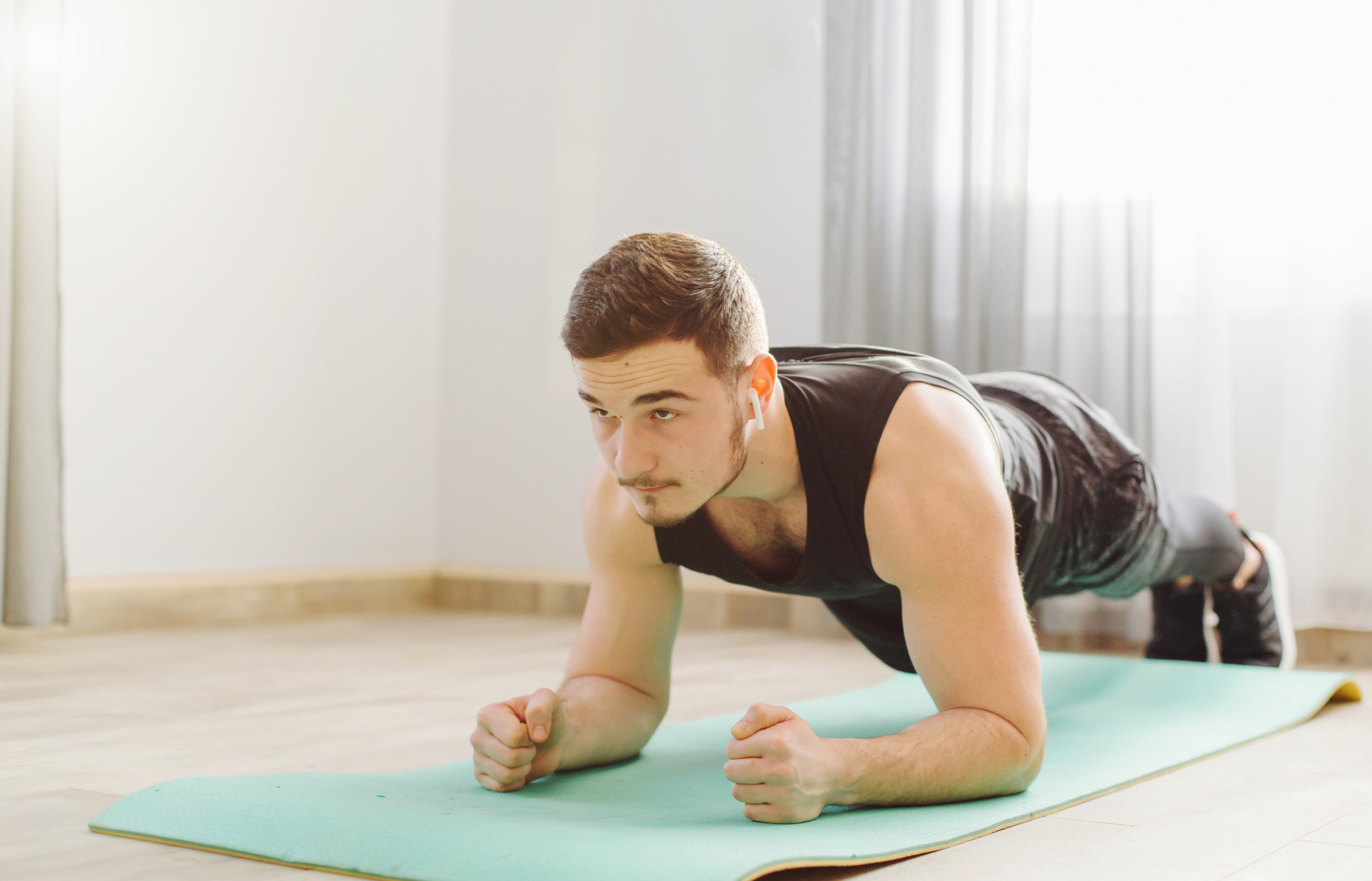 A man doing a plank exercise indoors to strengthen core muscles and improve posture.