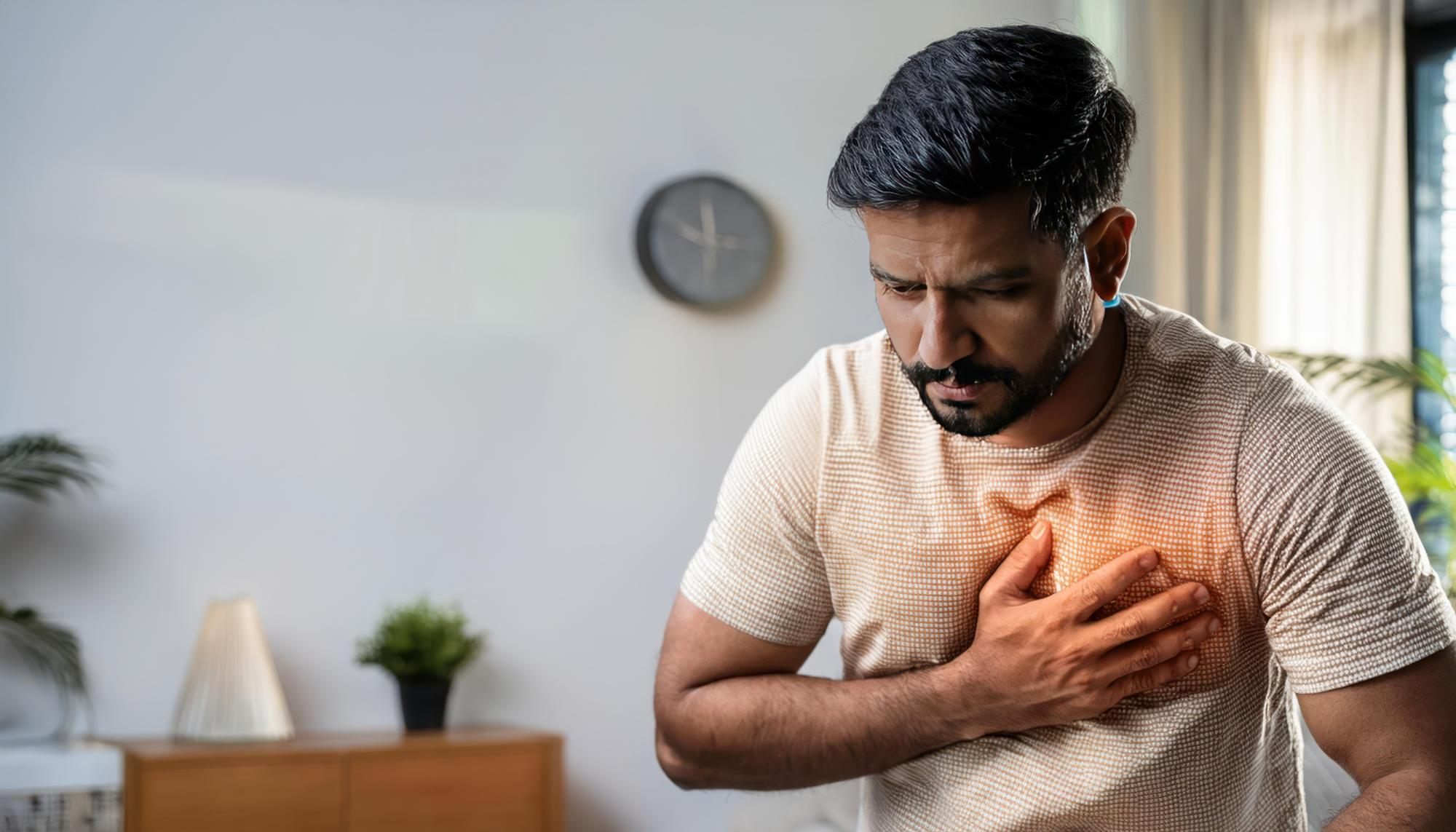 A man holding his chest in visible discomfort, representing a common symptom of heart-related conditions.
