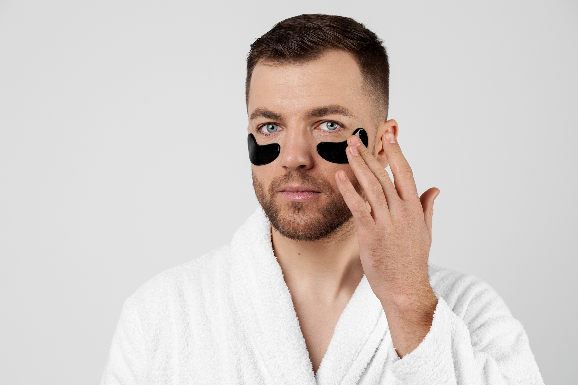 A man wearing under-eye patches to reduce dark circles and puffiness.