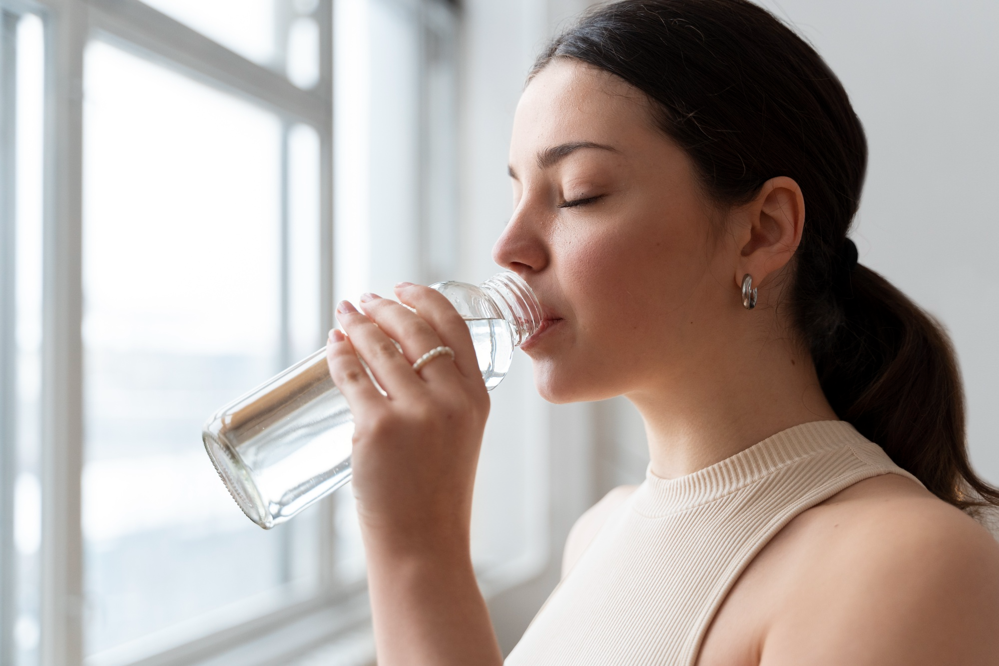 A woman drinking water, showing the importance of hydration to bone healing.