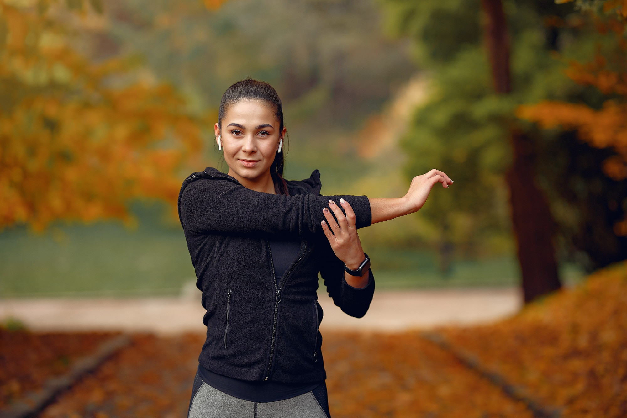 A woman in athletic clothes, stretching and warming up before an outdoor workout.