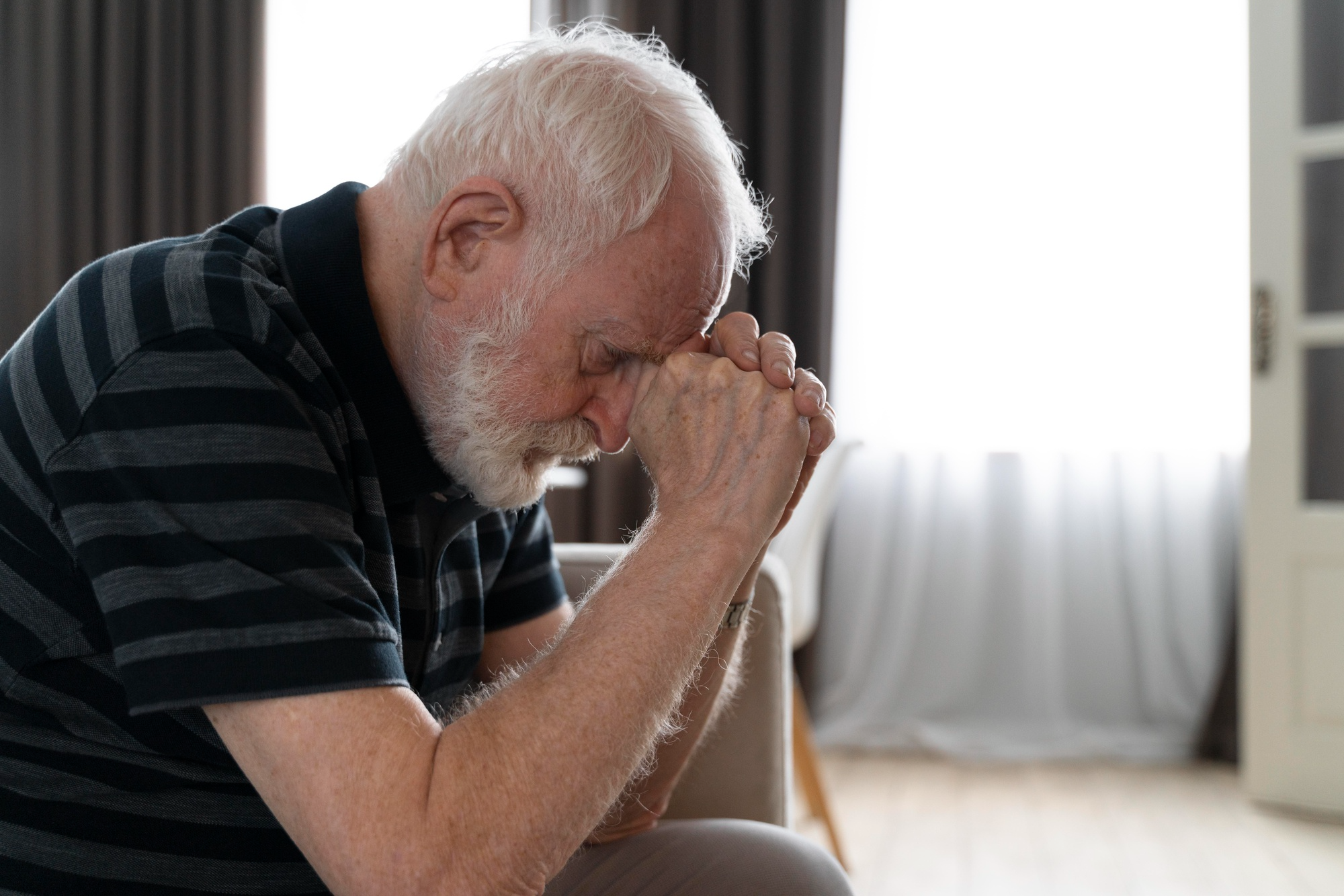 An older man sits quietly, appearing lost in thought, representing the cognitive decline and memory challenges associated with dementia.