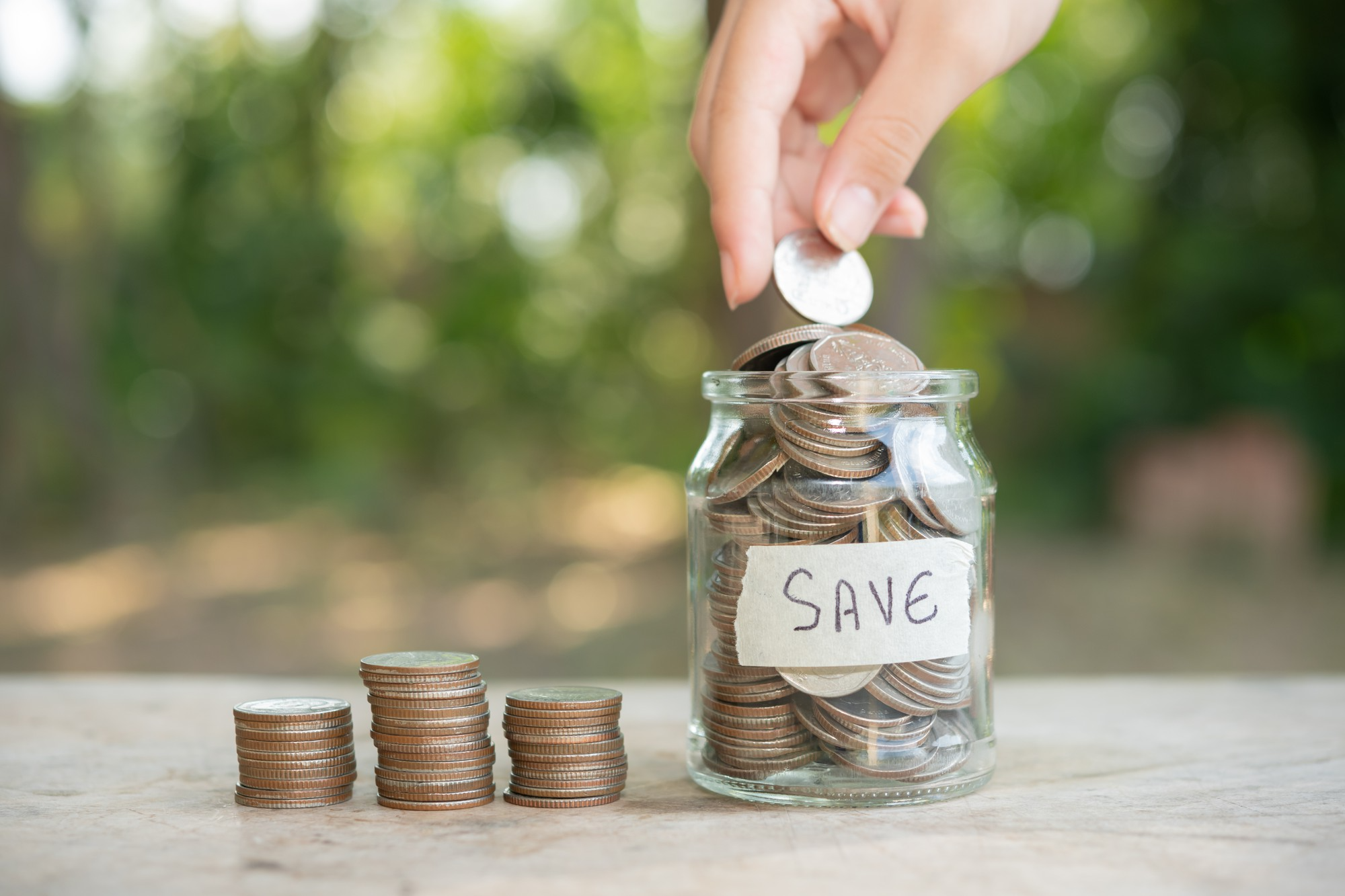 A close-up of hands adding coins to a savings jar, representing how personalized medicine and preventive care can help reduce long-term healthcare costs. Imade Description - Saving money through personalized medicine and preventive care.