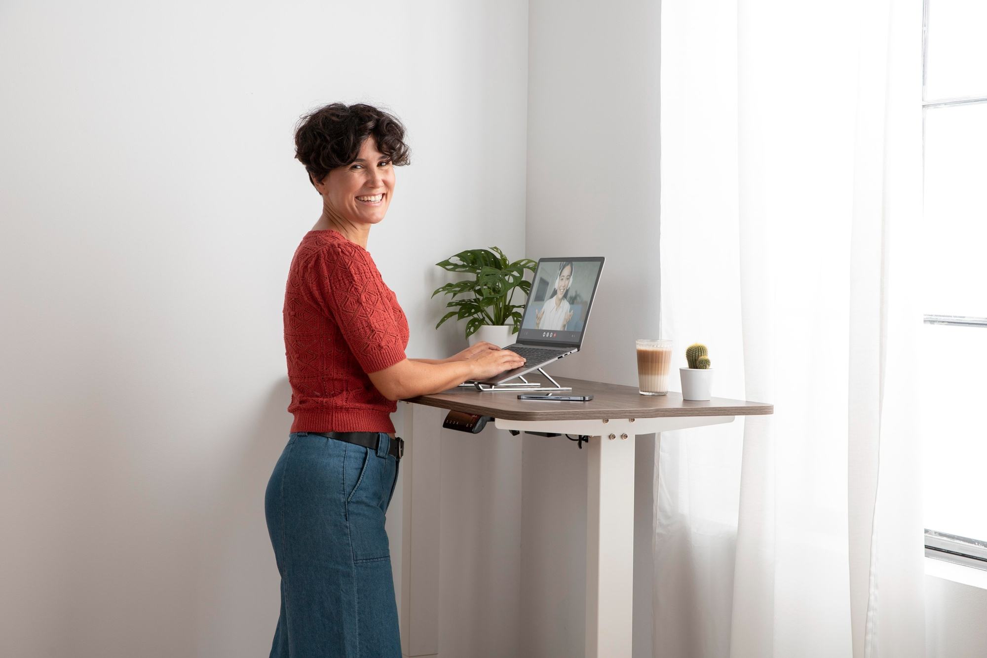 A professional woman using a standing desk while working on a computer, promoting better posture and active working habits.