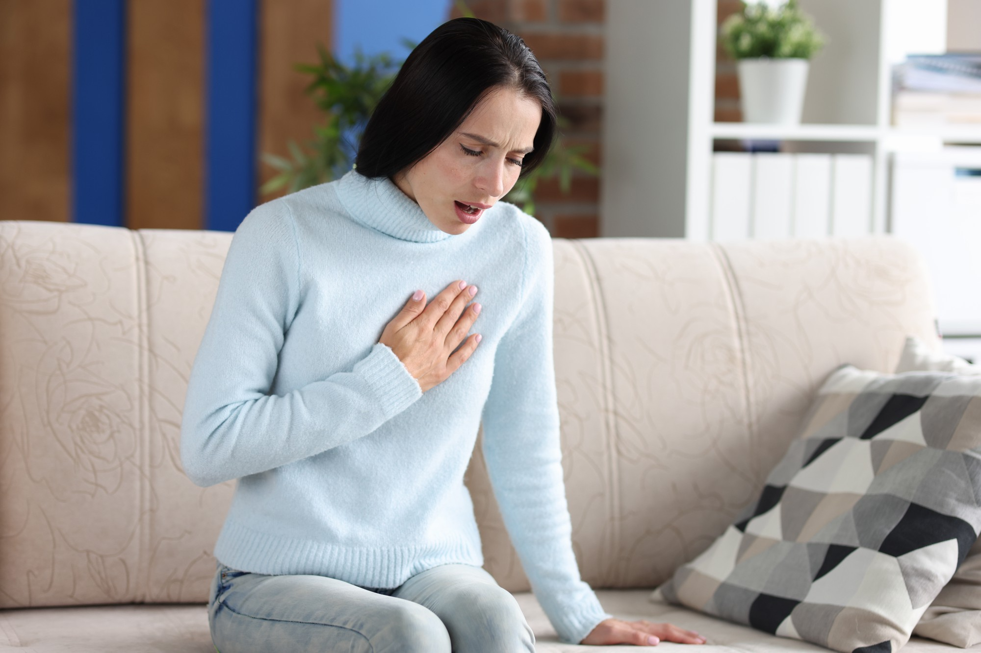 A woman clutching her chest in discomfort, representing warning signs of heart disease that are often overlooked in women.