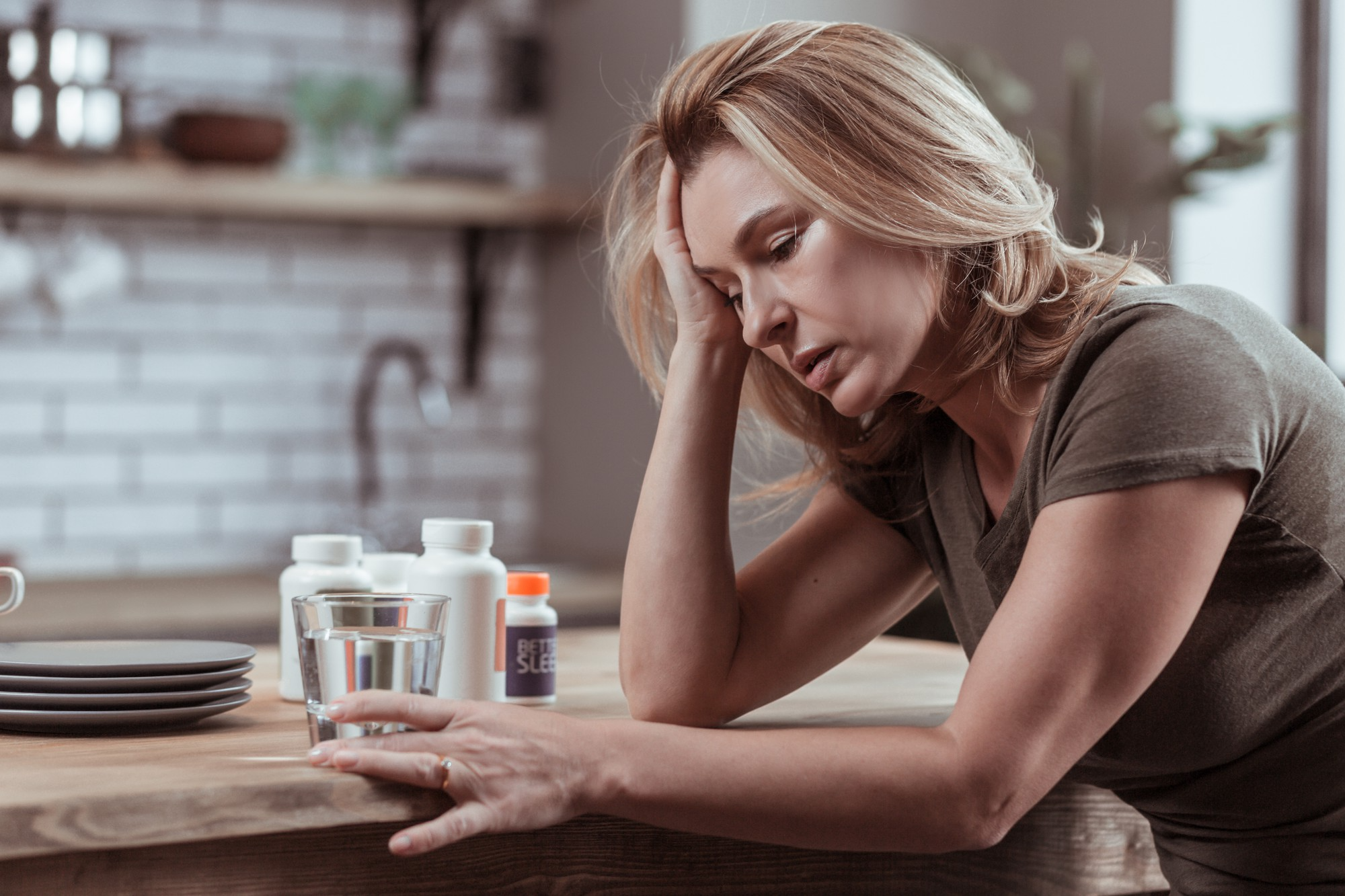 A woman feeling constant tiredness and fatigue, sitting with closed eyes and hand on forehead due to Vitamin D deficiency.