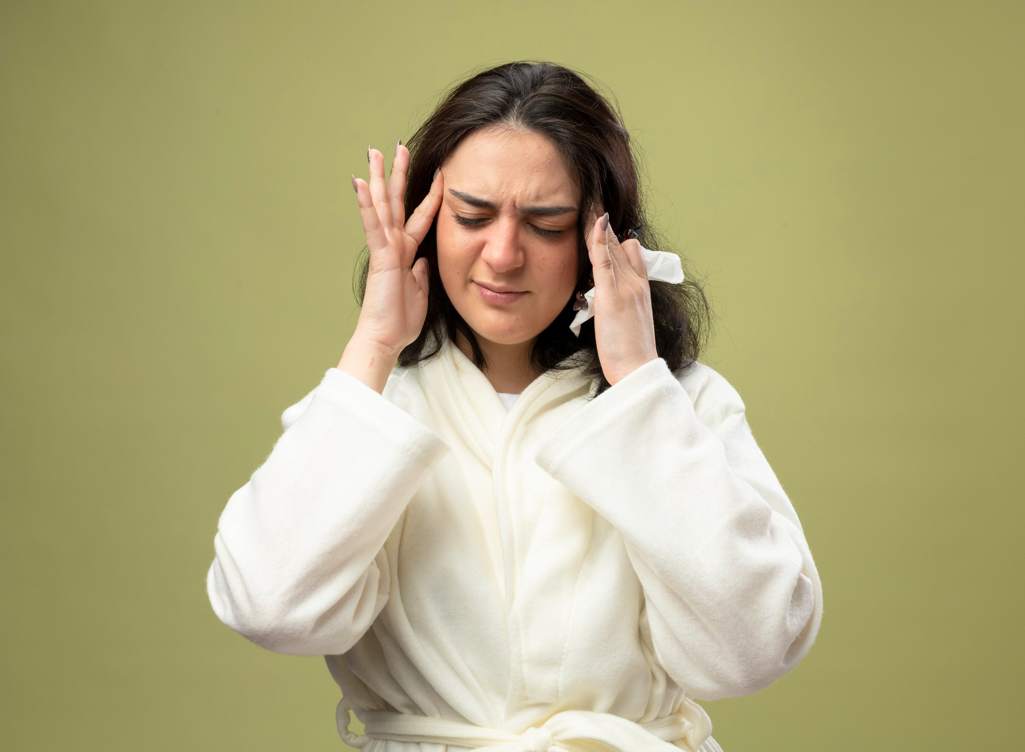 A woman holding her head, representing the intense throbbing pain and sensitivity commonly caused by a migraine, often accompanied by fatigue, nausea or sensitivity to light and sound.