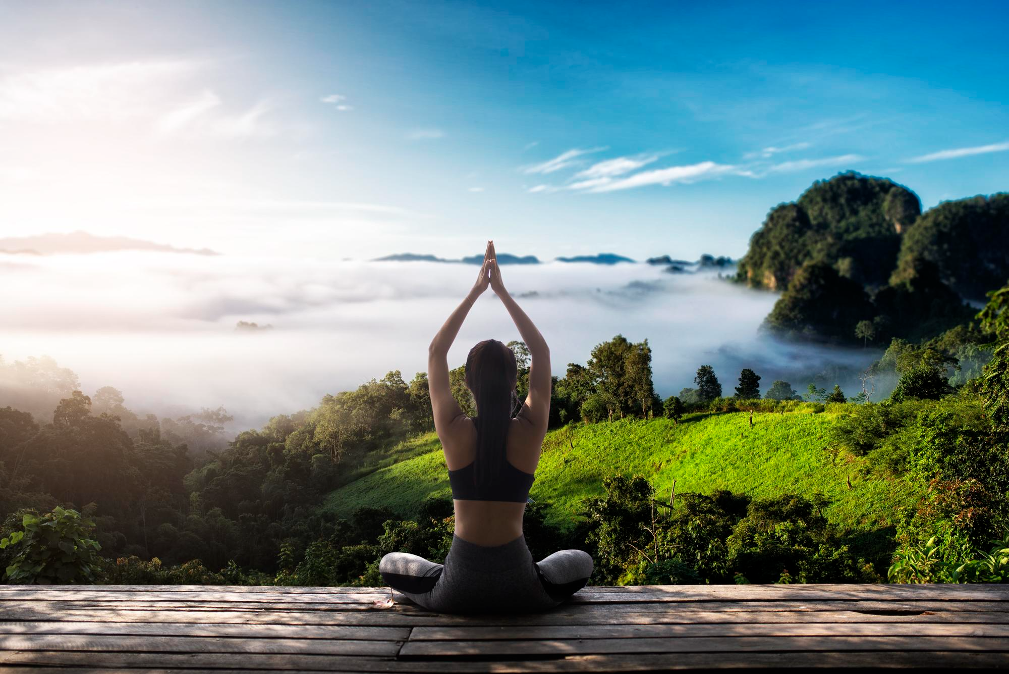 A woman performing yoga poses on a mat in a green outdoor setting, promoting mindfulness, flexibility and physical well-being.