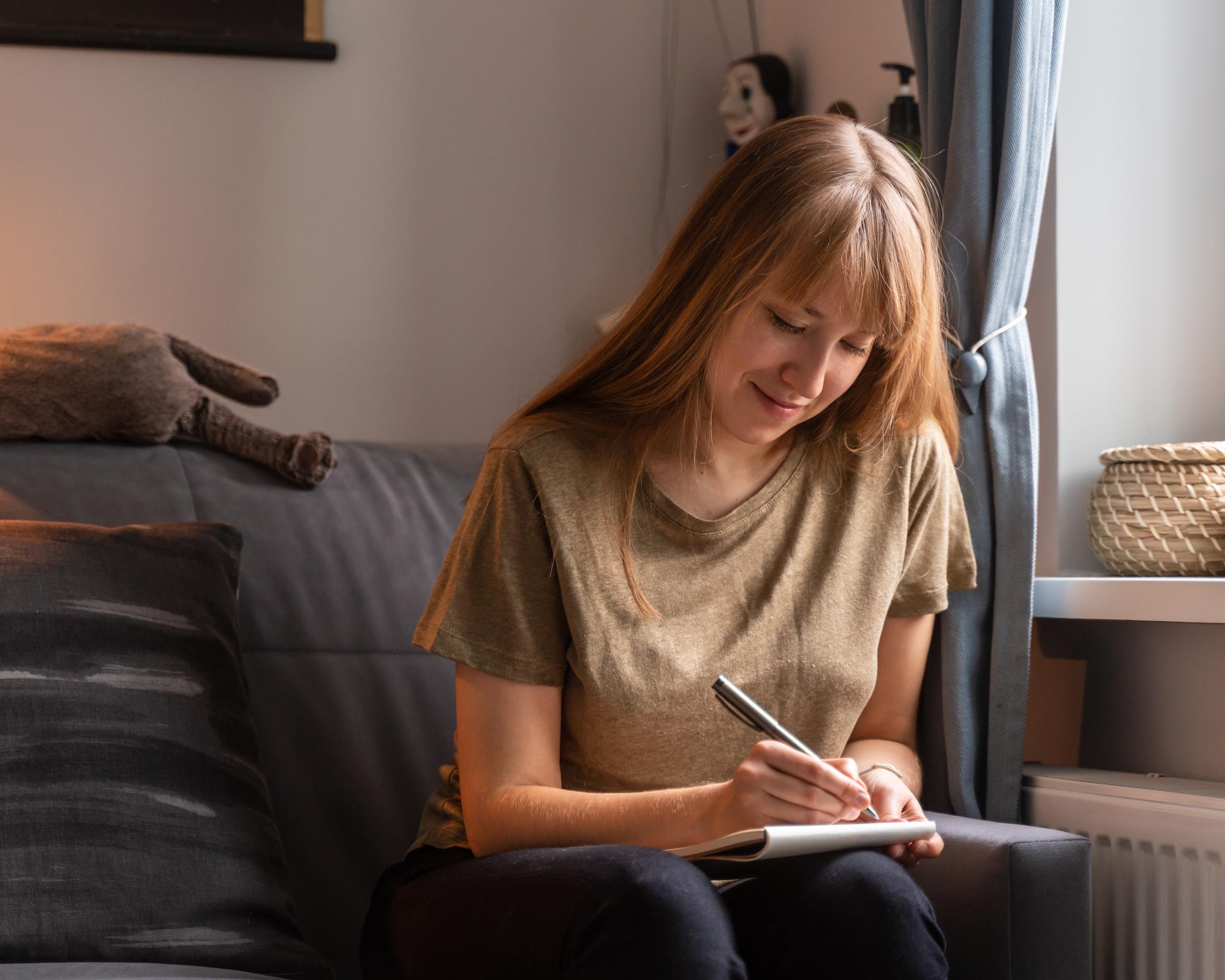 A woman writing in her journal in a calm setting, highlighting journaling as a powerful tool for self-reflection, emotional release and stress management.