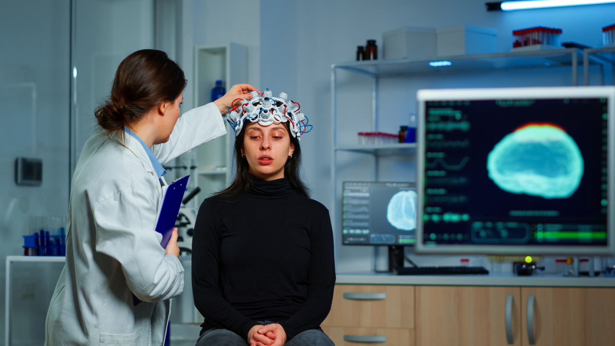 A patient undergoes a neurological examination using a head-mounted monitoring device in a clinical setting.