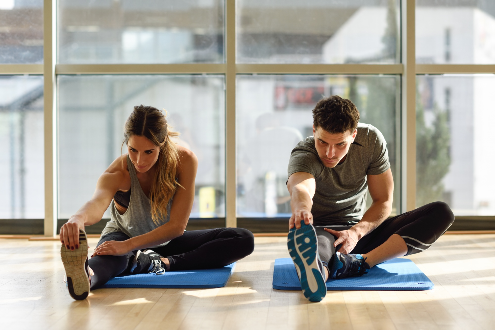 Two people doing light yoga stretching exercises together for flexibility and relaxation.