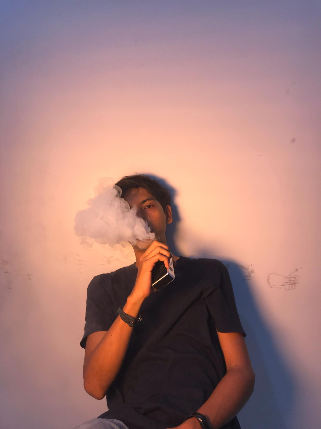  A person exhaling cigarette smoke in a dimly lit room.